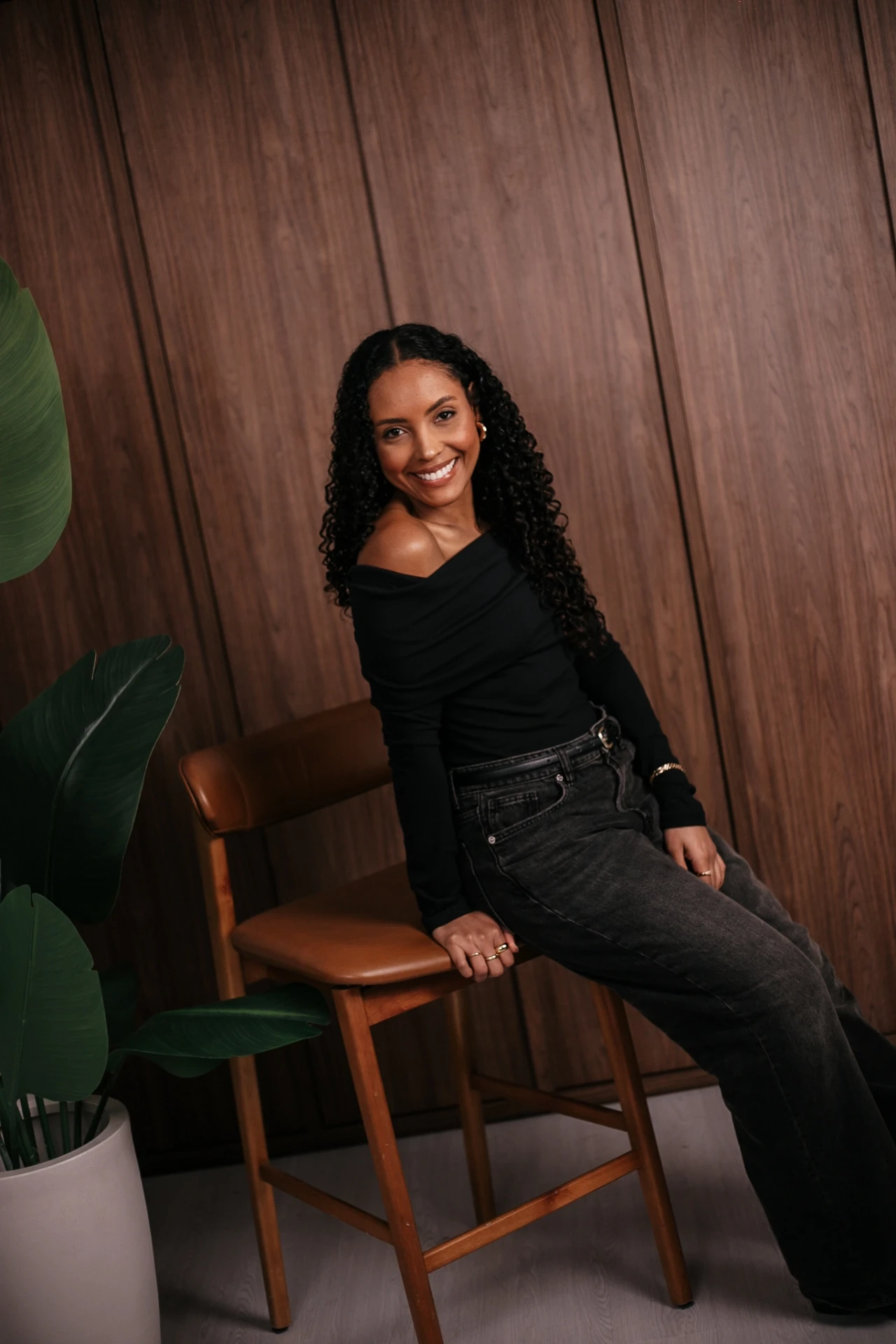 Retrato de Nathália Silveira sentada em um banco de madeira, sorrindo